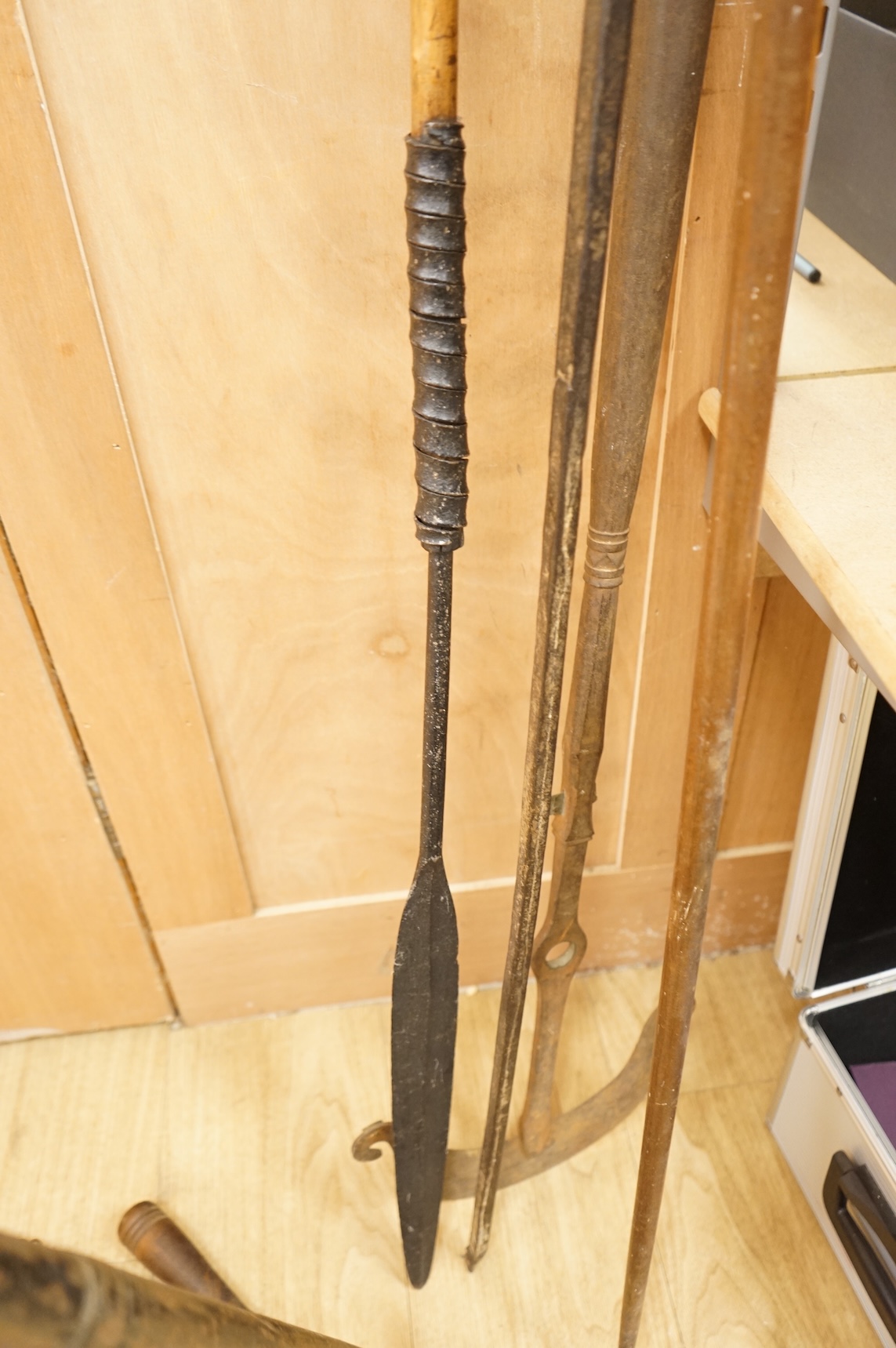 A collection of tribal spears, a fish hook, a cased snooker cue, etc.